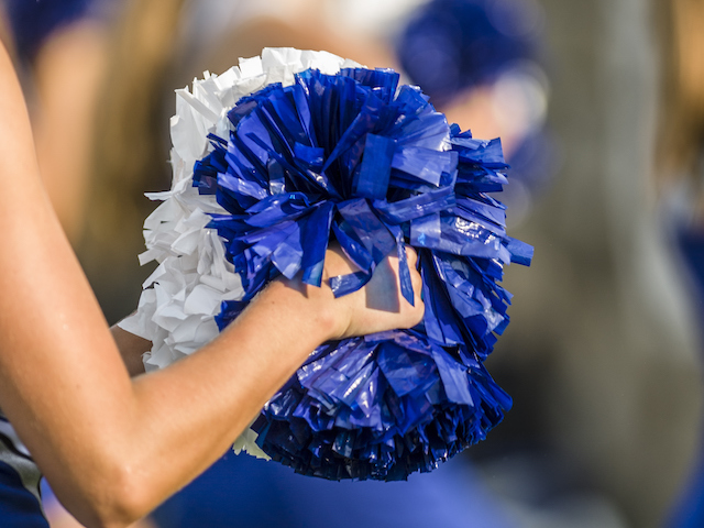 Cheerleader shaking blue and white pom poms